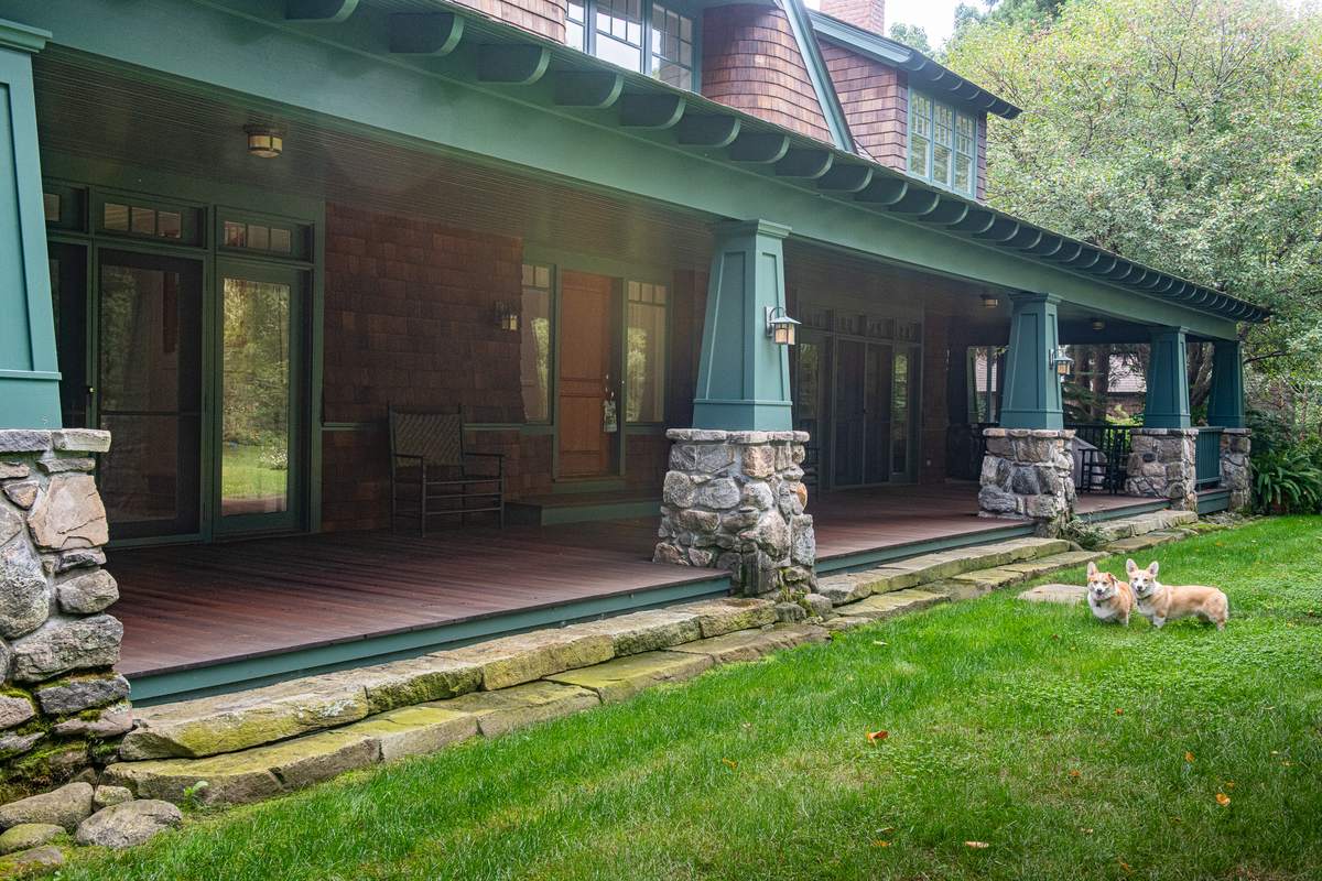 Long stone steps along a Craftsman porch with stone piers and green tapered columns