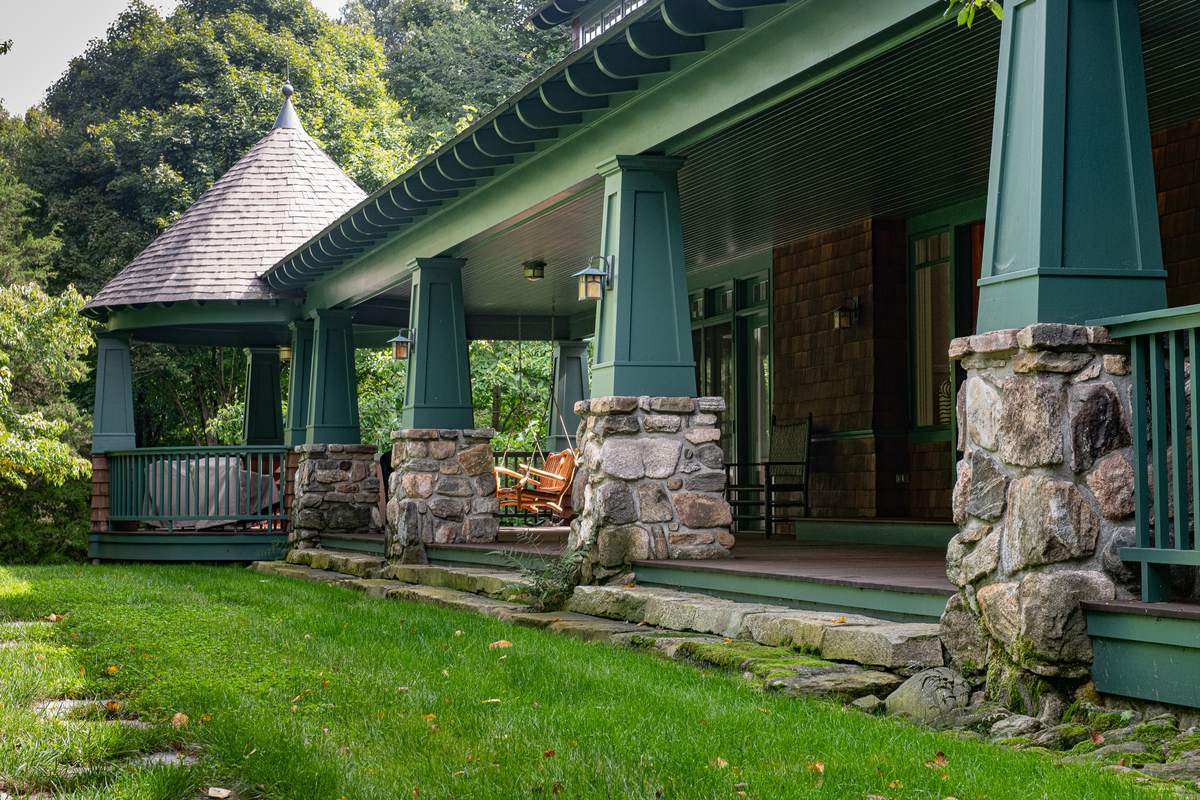 Stone steps following the porch toward a conical-roofed gazebo, with mossy stone piers