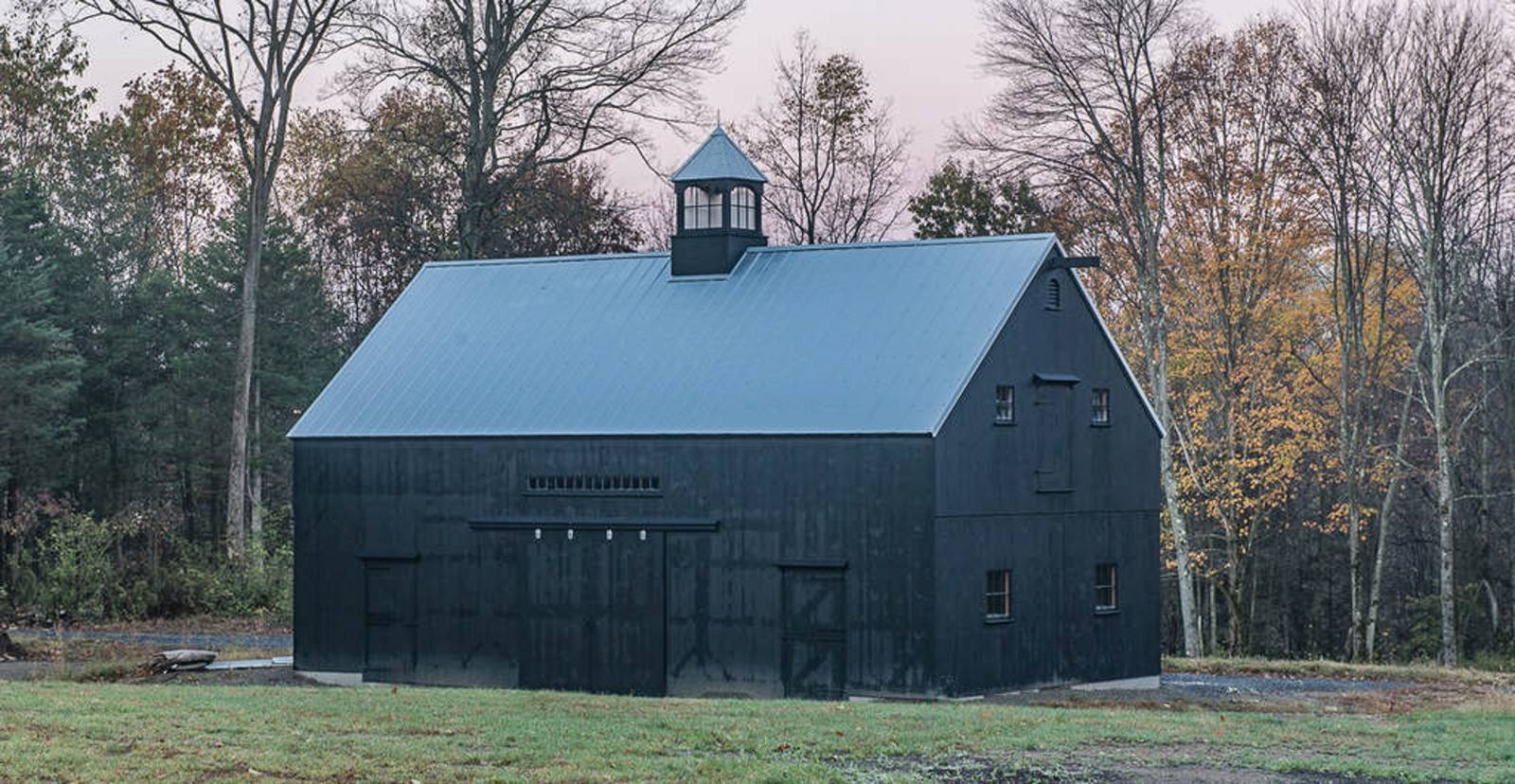 Black barn at dusk among fall trees