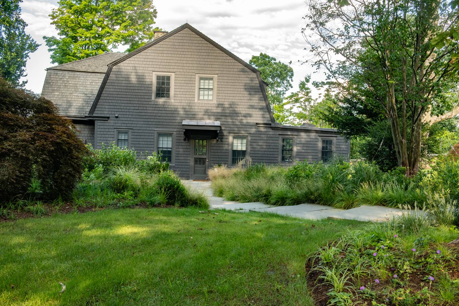 Dark shingled house with a garden of grasses and a bluestone walk