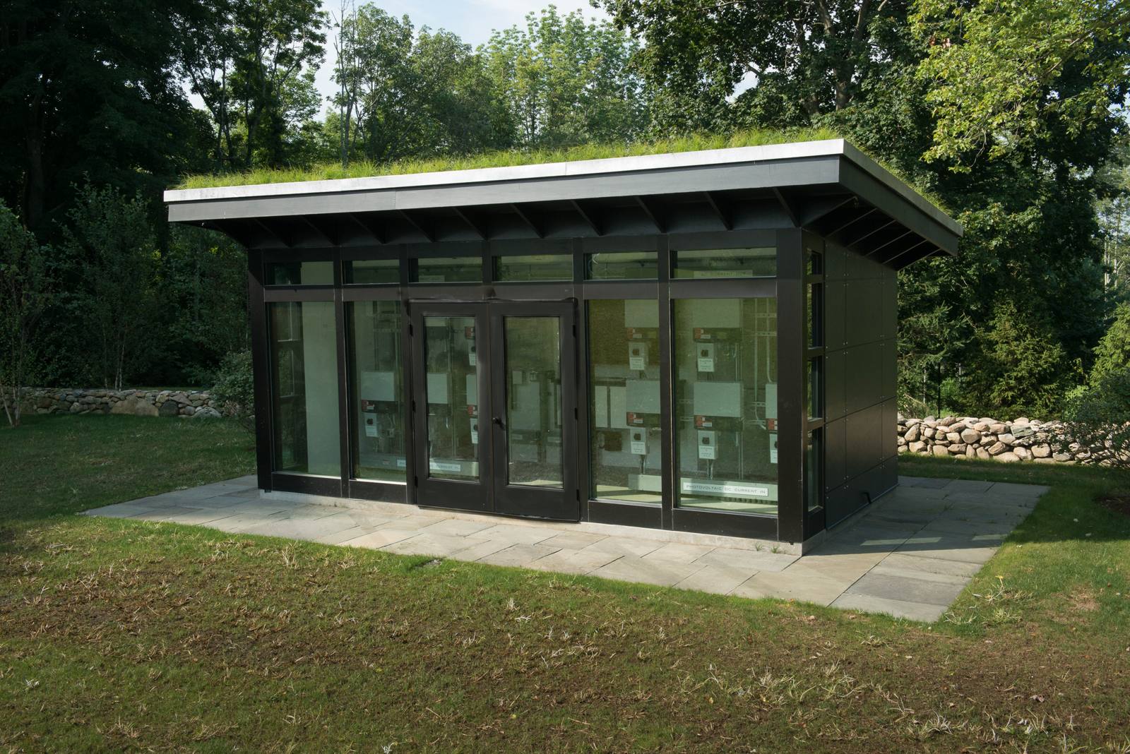 Equipment building with a green roof beside a stone wall