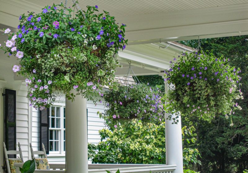 Three overflowing hanging baskets framed by white porch columns