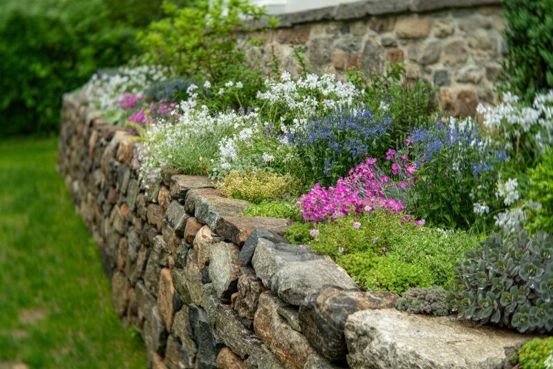 Dry-laid stone wall planted with phlox, dianthus and sedums