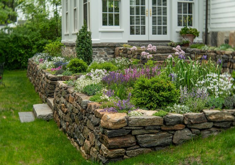 Tiered stone retaining walls planted with perennials below the conservatory
