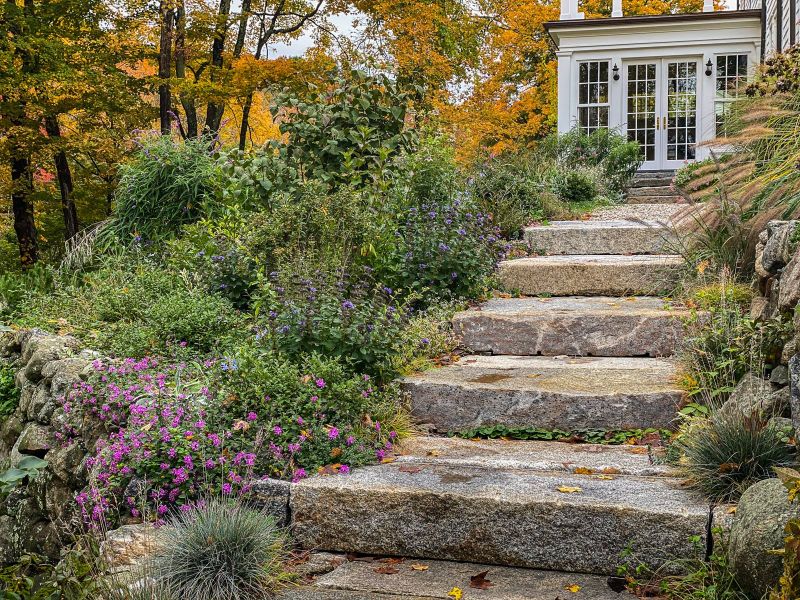 Wide granite steps rising through perennials toward the conservatory in autumn