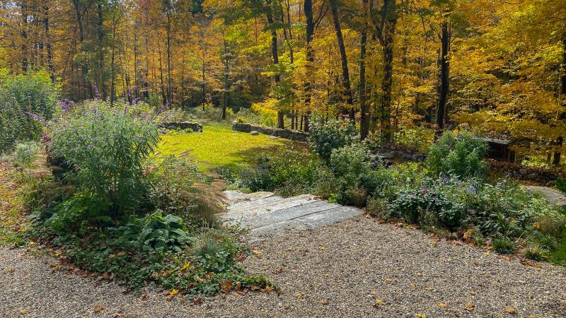 Granite steps and a gravel path overlooking a lawn and fall foliage