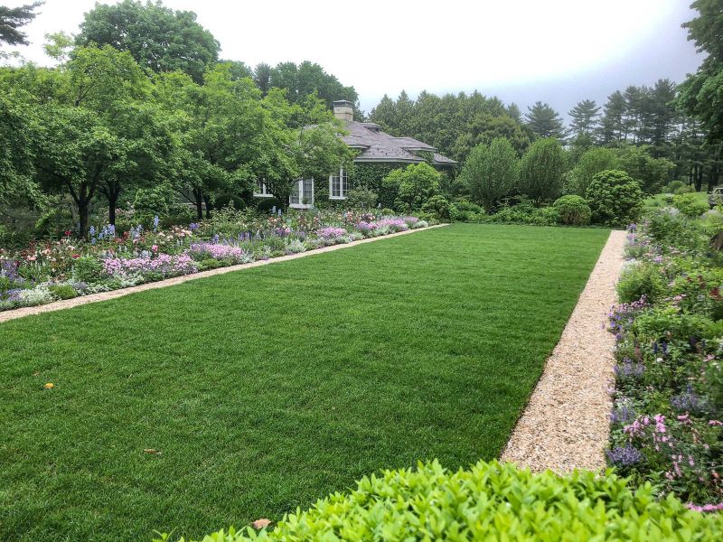 Long lawn framed by a gravel path and mixed border, with the garden house beyond