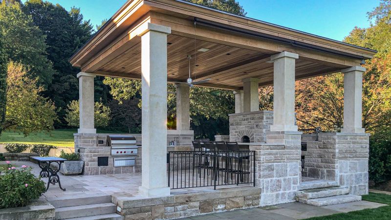 Limestone-columned pavilion with bleached cedar ceiling, outdoor kitchen and bar above the garden