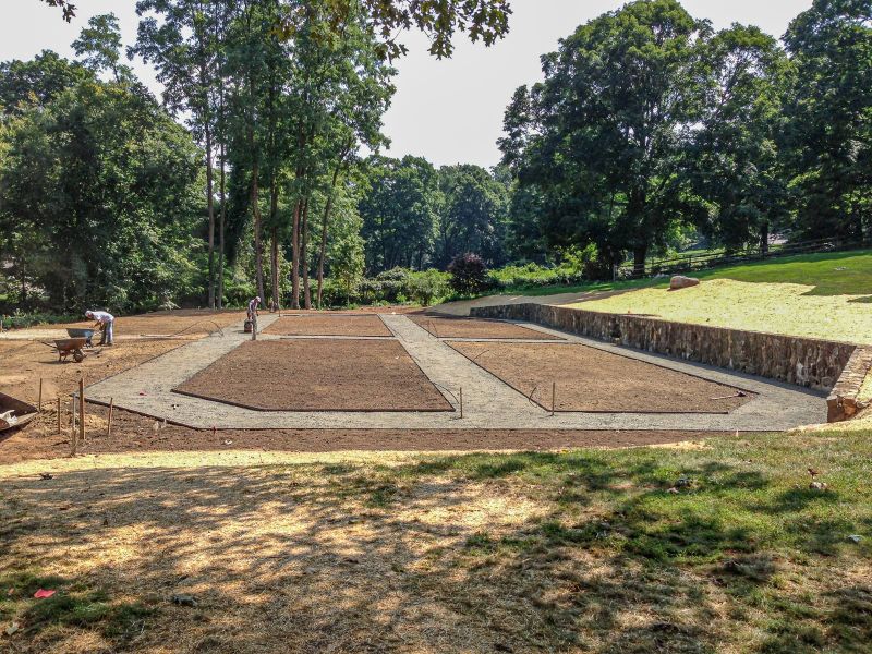Steel-edged beds divided by gravel paths with the crew leveling soil