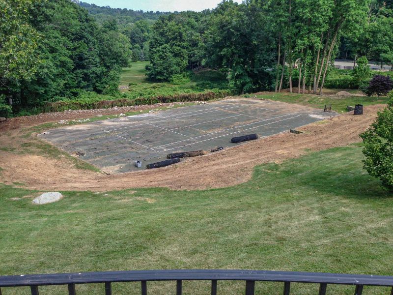 Abandoned tennis court with weathered surface before construction