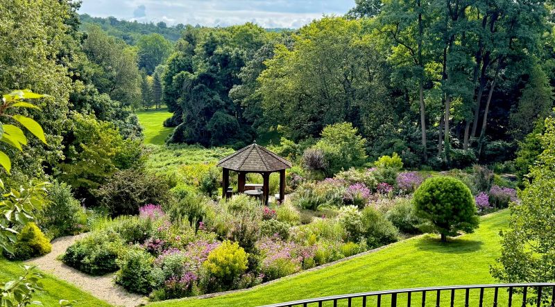 Gazebo at the heart of the cutting garden seen from the house terrace, with gravel paths and lawn
