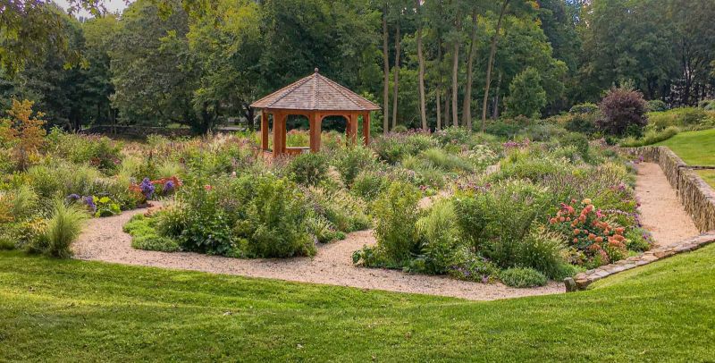 Cedar-shingled gazebo at the center of the cutting garden, with gravel paths and a stone retaining wall