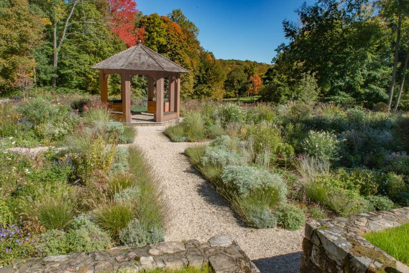 Gravel path between lavender, artemisia and grasses leading to the gazebo in autumn
