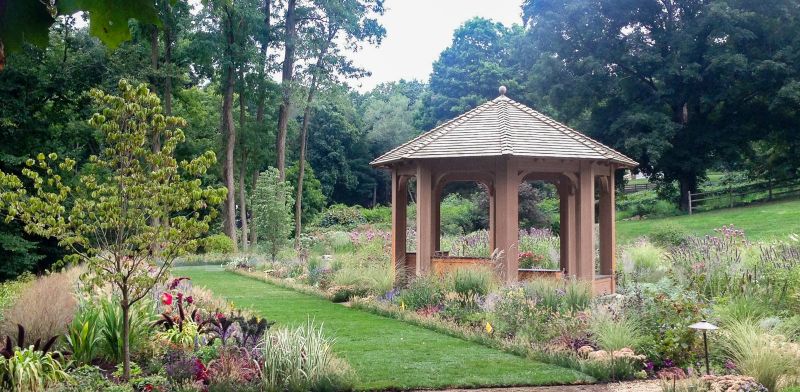 Gazebo beside a lawn path and mixed borders of grasses, salvia and sedum