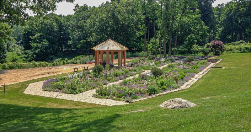 Planted cutting garden with gazebo, gravel paths and a stone retaining wall seen from the lawn above