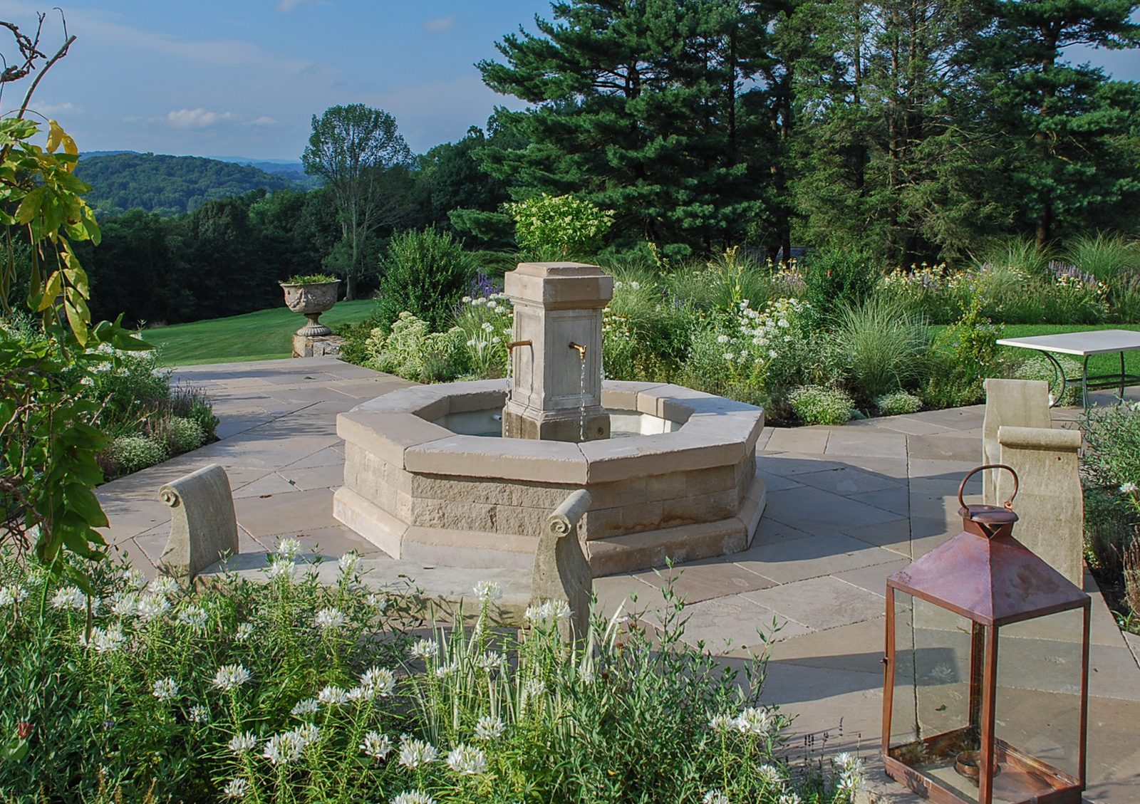 Terrace fountain with carved stone benches and a copper lantern